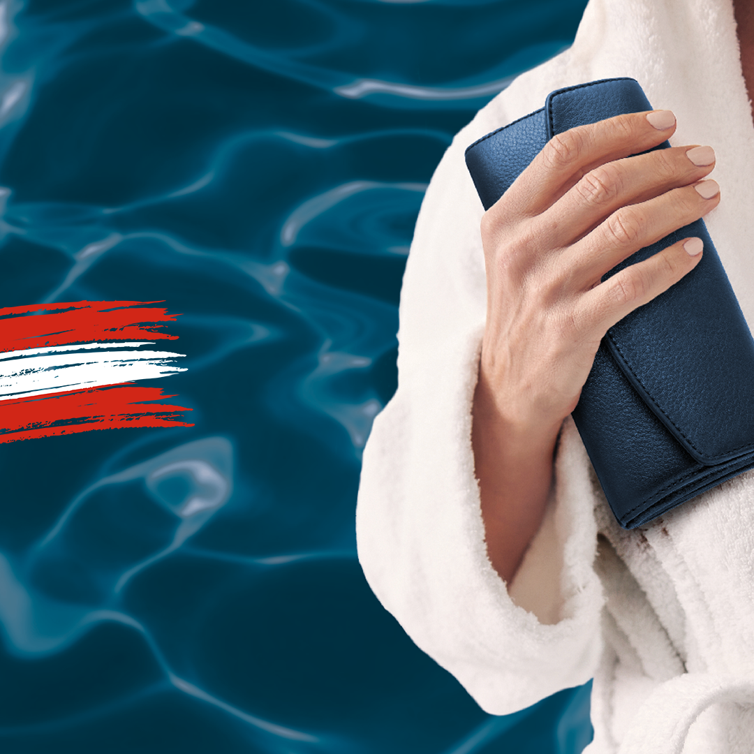 Eine Person in einem weißen Gewand hält eine blaugrüne Clutch vor einem Hintergrund aus plätscherndem blauem Wasser mit roten und weißen Pinselstrichen an der Seite.