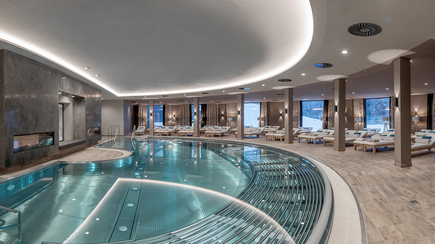 Erleben Sie die ultimative Entspannung in unserem luxuriösen Indoor-Day-Spa mit großem Pool, bequemen Liegestühlen und beruhigender Ambientebeleuchtung.