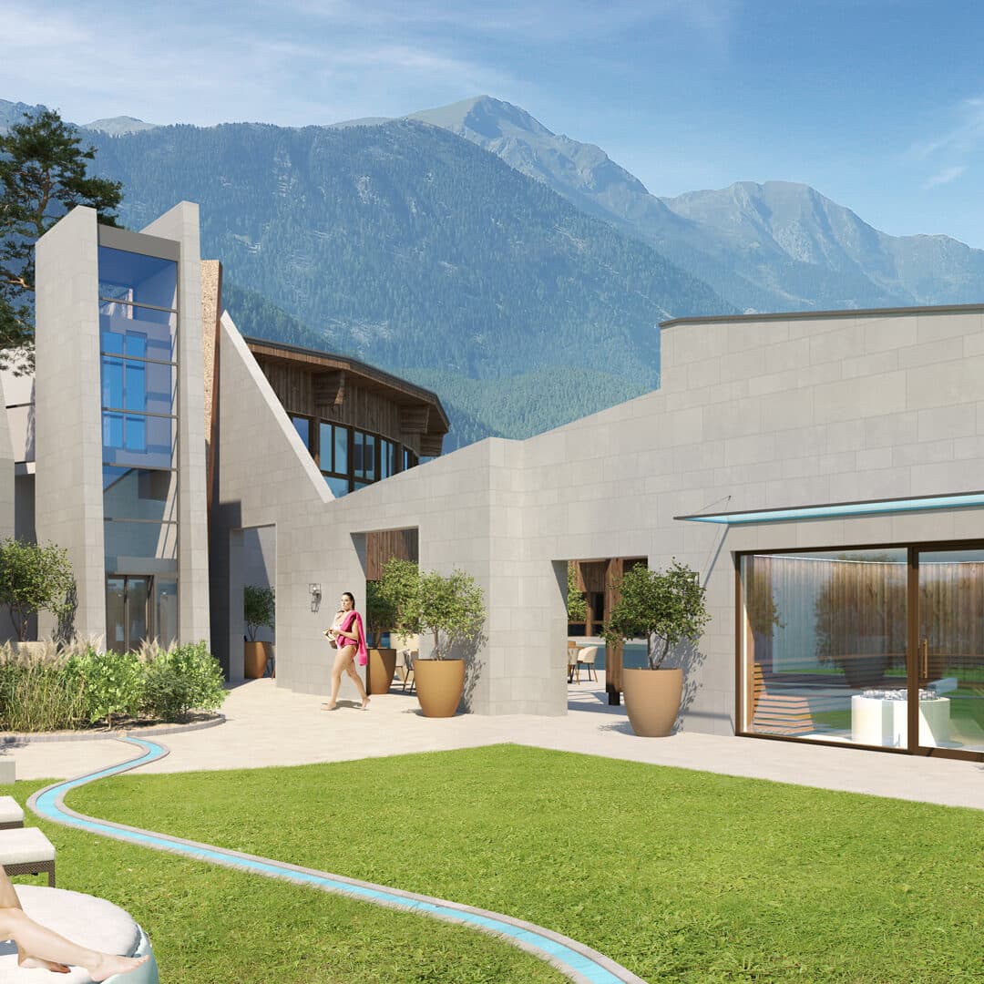 Modernes Gebäude mit eckigem Design, großen Fenstern und Topfpflanzen an einem sonnigen Tag, vor der Kulisse von Bergen und blauem Himmel. Eine Person in Pink geht im Innenhof spazieren.