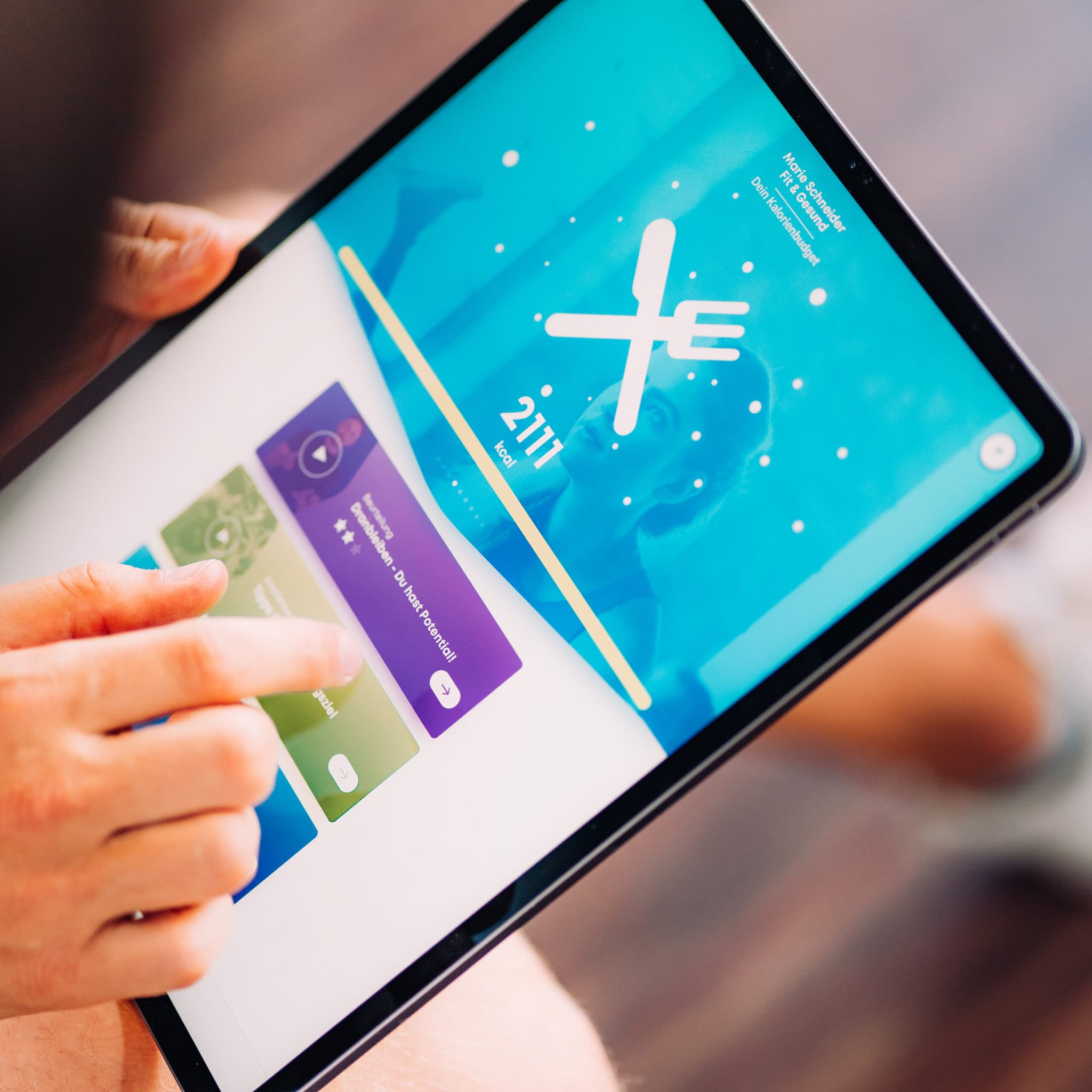 Person, die ein Tablet mit einer Fasten- oder Diätverfolgungs-App verwendet; der Bildschirm zeigt ein Gabel- und Messersymbol, einen Countdown-Timer und farbige Menüoptionen.
